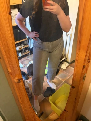 Grå raka jeans med hög midja - Säljer ett par grå jeans med rak passform och hög midja. Jeansen har klassisk femficksdesign och croppad längd som slutar ovanför ankeln. Perfekta till en avslappnad och trendig stil. Storlek 44, ifrån bershka