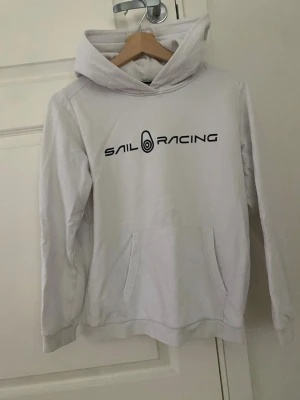 Vit hoodie från Sail Racing - Snygg vit hoodie från Sail Racing med svart logga tryckt på bröstet , storlek 160 