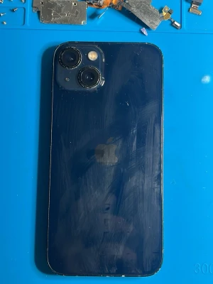 Svart iPhone med dubbla kameror - Säljer en marin blå iPhone 13 med stilren design och rundade hörn. Baksidan har två kameror placerade i hörnet och den klassiska Apple-loggan i mitten. Mobilen har en glasbaksida och metallram. Perfekt för dig som gillar snygg och modern teknik.