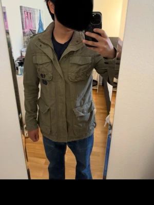 Tommy Hilfiger Field jacka  - Säljer en field jacka från Tommy Hilfiger. Den passar S/M, storleken är egentligen 176 i barnstorlek men den är stor i storleken. Den är för lång för mig som är 170. Därför skullle jag säga att den passar ca 175+. Den är väl omhändertagen och har inga tecken på användning.