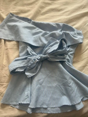Blåvit offshoulder topp med knyt - Snygg blåvit randig offshoulder topp med bred volang upptill och knyt i midjan. Köpt på vinted så vet ej vart den är ifrån men antar shein 