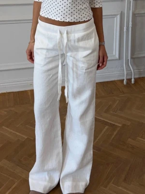Everyday linen pants - Säljer ett par vita linnebyxor med breda ben och hög midja. Byxorna har dragsko i midjan för skön passform och är gjorda i ett luftigt linnetyg. Perfekta för en avslappnad och trendig look i sommar.