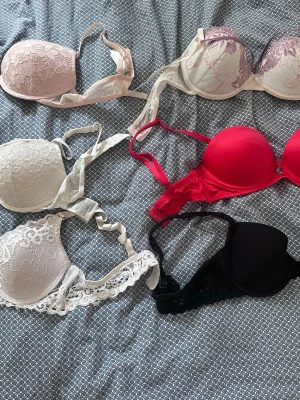 Mix av spets- och pushup-bhar - Säljer ett paket med fem bhar i olika färger och modeller. Inkluderar spets-bh i ljusrosa, vit och beige, en röd pushup-bh samt en svart bh med spetsdetaljer. Alla har reglerbara axelband och bygel för extra stöd. Perfekt för dig som vill ha variation i underklädeslådan.