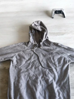 Kashmyr tröja/hoodie - En enkel och stilren grå hoodie med huva och dragsko. Hoodien har långa ärmar och är gjord i ett mjukt material som känns skönt mot huden. Perfekt för chill dagar eller när du vill ha en avslappnad look. Passar S och även Xs