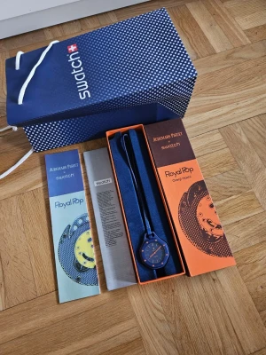 Audemars Piguet x Swatch Orenji Hachi Royal Pop - Unik Swatch Royal Pop Orenji Hachi klocka i samarbete med Audemars Piguet. Klockan har en cool blå färg med orange detaljer på urtavlan och visarna. Kommer i originalförpackning med snygg presentpåse och manual. Perfekt för dig som gillar statement-accessoarer.