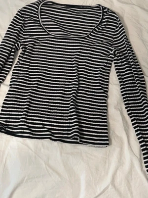 Svartvit randig långärmad topp - Snygg långärmad topp med svartvita ränder och rundad urringning. Tunn och mjuk i materialet.