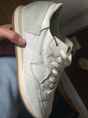 Vita sneakers med mockadetaljer - Snygga vita sneakers med detaljer i mocka och textil. Skorna har vita snören, låg profil och en klassisk sula i gummi. Perfekta för en clean och stilren look. Passar till det mesta och är riktigt bekväma.