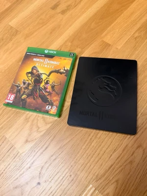 Mortal Kombat 11 Ultimate Xbox - Mortal Kombat 11 Ultimate till Xbox, inklusive originalfodral och exklusivt svart steelbook-fodral med Mortal Kombat-loggan. Spelet har en grön plastbox och skivan har snygg grafik med spelets ikoniska drake. Perfekt för dig som gillar fighting och samlarutgåvor. Steelbook 