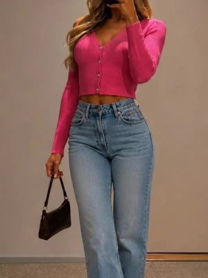 Rosa cropped ribbad kofta från Zara - Trendig rosa cropped kofta med ribbad struktur och V-ringning. Koftan har långa ärmar och knäpps med silvriga knappar framtill. Perfekt att styla med höga jeans för en cool look.