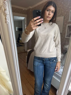 Beige rundhalsad tröja - Snygg beige tröja med rund halsringning och diskret broderad logga på bröstet. Tröjan har långa ärmar och ribbade muddar vid ärmslut och nederkant. Perfekt att matcha med jeans för en clean look. Tröjan är krympt i tvätten, ordinarie storlek är 2xl men skulle säga att den nu är st S