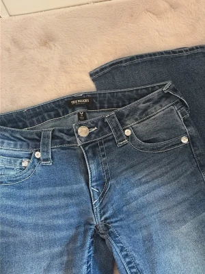 True Religion Jeans Blå - Säljer ett par klassiska blå jeans från True Religion med låg midja, då jag behöver mer utrymme i garderoben 💗Endast använda ett fåtal gånger och i nyskick, inga slitningar. Priset är förhandlingsbart!