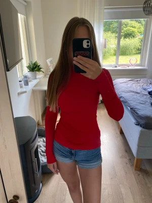 Röd polotopp med lång ärm - Snygg röd polotopp med lång ärm och tight passform. Perfekt att styla med jeans eller kjol för en trendig look. Materialet känns mjukt och stretchigt, vilket gör toppen bekväm att bära hela dagen.
