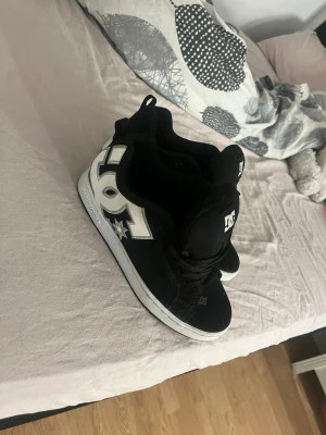 Svarta DC sneakers med vit logga - Säljer pågrund av att dom är för små dom är i väldigt bra skick förutom att dom är lite slitna vid hälen pågrund av att dom är för små för mig köpte för ca 1000kr 