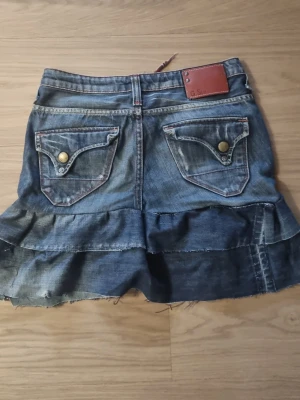 Jeanskjol med volang och rå kant - Cool jeanskjol i blå denim med volangdetalj och rå, fransig kant nertill, gjord av mig, från märket gstar raw, dragsko i midjan.  #baggyjeans #lowwaist jeans #cargobyxor #vida jeans #flarejeans #lågmidja #rakajeans #kostymbyxor #mjukisbyxor #oversizedhoodie #ziphoodie #stickadtröja #corsettopp #offshoulder #babytee #linne med spets #oversized tshirt #stickadväst #maxikjol #y2k #vintage #streetwear #oldmoney #cleangirl #basic #festkläder #vardagskläder #unisex #oversized #fitted #cozy zara hm