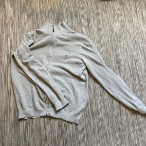 Ljusgrå ziptröja från Sir Raymond Tailor - Ljusgrå ziptröja från Sir Raymond Tailor med diskret logga på bröstet. Tröjan har hög krage, hel dragkedja och är tillverkad i ett mjukt stickat material. Perfekt för lager-på-lager och enkel att matcha med andra plagg. Hör av dig vid frågor// kan gå ner i pris vid snabb affär!😃/ Milton