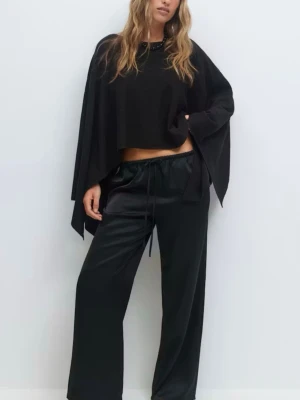 Svart ponchotröja med vida ärmar - Säljer en svart ponchotröja med oversized passform och vida, fladdriga ärmar. Tröjan har en lös siluett och är tillverkad i ett mjukt, tunt material som faller snyggt. Perfekt för dig som gillar en avslappnad och trendig stil.
