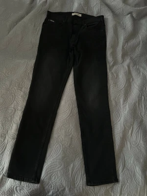 Svarta slim fit jeans från Lindbergh - Säljer svarta slim fit jeans från Lindbergh med klassisk femficksdesign och normal midja. Jeansen har en lätt tvättad look och raka ben. Sparsamt använda.
