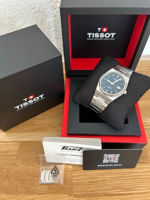 Tissot PRX silver klocka blå urtavla - Till salu är en Tissot Powermatic 80 med blå urtavla och 40 mm boett i mycket fint skick. En elegant och pålitlig automatisk klocka med Tissots uppskattade Powermatic 80-urverk. Boetten, glaset, boettlocket och armbandet är i mycket fint skick med endast minimala spår av användning. Komplett med originalpapper och tillbehör. Finns mindre hårsling repor men svårt att se.  Ingår: • Original Tissot-box • Original garantikort/papper • Kvitto från Stjärnurmakarna • Originalarmband