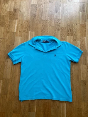 Turkos pikétröja från Polo Ralph Lauren - Väldigt fin Pikétröja från Ralph Lauren. Tröjan är i väldigt fint skick och har inte används så mycket alls.   Storlek: XL, men passar size L och M också.   Det finns inga hål eller missbildningar men ett av knappöppningarna är lite löst, vilket självklart går att lösa genom att sy.  Bredd: 49,5cm  Axelbredd: 44cm  Längd: 60cm  Skickas så fort som möjligt!🥰  