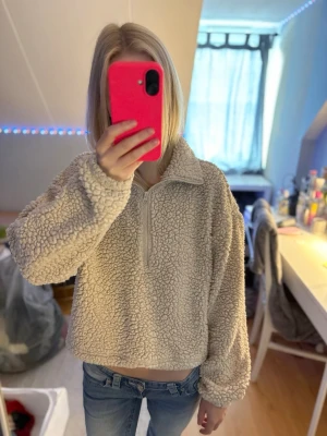 Fluffig hoddie  - Säljer min ljusa fluffiga hoodie som är perfekt på vintern. På sista bilderna syns det en svart fläck jag inte fått bort men syns inte när den används och inget man tänker på om man inte tar en närmare titt. På näst sista bilden ser man att man kan dra åt den där nere vid midjan/magen. Skriv om frågor. (Priset går alltid att diskutera)
