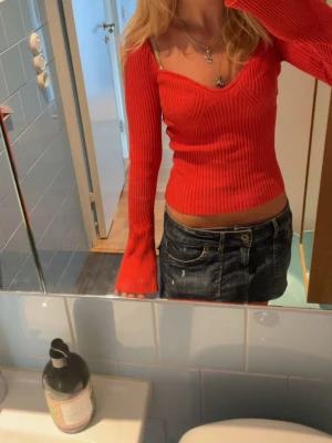 Ribbad orange/röd croppad topp - Trendig röd ribbad topp med lång ärm och croppad passform. Toppen har en snygg v-ringning och sitter tight mot kroppen. Perfekt för dig som vill ha en färgstark och figurnära look.