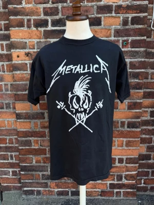 Vintage Metallica T-shirt – Shit in the Sheds Summer of ’94 – Single Stitch – 90-tal - Ovanlig vintage Metallica T-shirt med klassiska Shit in the Sheds – Summer of ’94-motivet. Stort tryck fram och turnétryck bak. Premium Five Star, 100 % bomull, Made in Pakistan. Märkt One Size Fits All, motsvarar ca L/XL. Single stitch i ärmar och nederkant. Mycket fint vintageskick med lätt naturlig fading.  Se bilder för skick  Mått: armhåla–armhåla 58cm, längd 78cm.