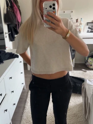 Vit croppad stickad topp - Säljer en enkel och stilren beige croppad topp med korta ärmar. Toppen är stickad och har en mjuk känsla, perfekt till jeans eller kjol. Passformen är loose och toppen har en rund halsringning. Ifrån Gina Tricot.🤗beige/ vit, kräm vit färg