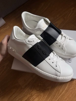 Valentino Open, storlek 43 - Säljer ett par helt oanvända Valentino Garavani Open sneakers i strl 43, köpta från Mytheresa. Aldrig använda, i nyskick! Allt medföljer inkl kvitto, dustbag och originalbox.  Hör av dig vid frågor eller intresse. 