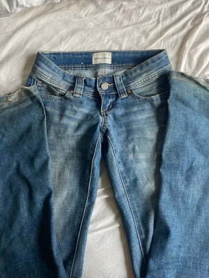 Blå jeans från Abrand Jeans - Ett par klassiska blå jeans från Abrand Jeans med fem fickor och dragkedja. Jeansen har en snygg tvättad look med ljusare partier framtill och slitningar vid fickorna. Perfekta för en avslappnad och trendig stil.