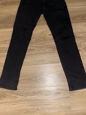 Svarta raka jeans - Svarta jeans med rak passform och klassisk femficksdesign. Jeansen har normal midja och är tillverkade i ett stretchigt denimtyg som ger en bekväm känsla. Perfekta för en stilren och enkel look.