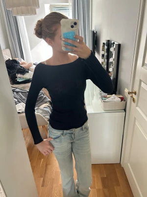 Svart ribbad långärmad topp - Säljer en svart, ribbad långärmad topp med rundad halsringning. Toppen har en slim passform och är tillverkad i ett stretchigt material som sitter snyggt på kroppen. Perfekt att styla med jeans eller kjol.
