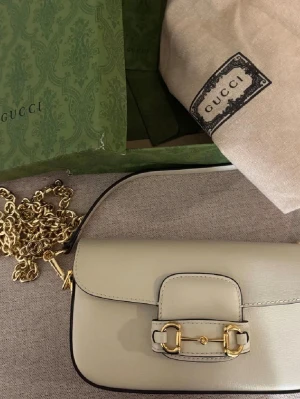 Beige handväska  - Snygg beige handväska i slätt läder med guldfärgad kedja, kommer med dust bag och box 