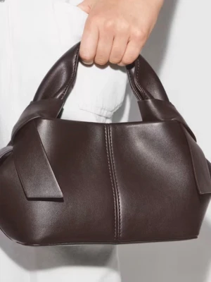 Mörkbrun handväska  - Snygg mörkbrun handväska med unik form och breda handtag. Väskan har en slät yta i läderimitation och dekorativa sömmar framtill. Perfekt accessoar för dig som vill ha en stilren och modern look.