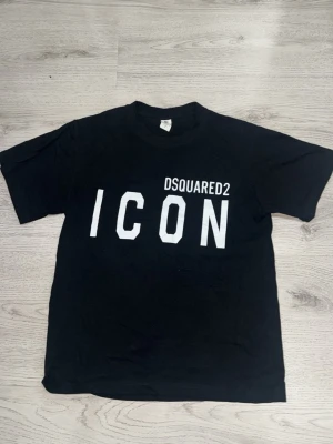 Svart ICON t-shirt från Dsquared2 - Snygg svart t-shirt från Dsquared2 med stor vit text 'ICON' på bröstet. Klassisk passform och rund halsringning. Perfekt för dig som vill ha en statement-tee med streetkänsla.
