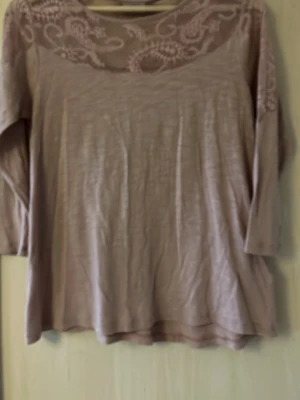 Rosa blus med spets från KappAhl - Söt ljusrosa blus från KappAhl med långärmad design. Blusen har ett transparent spetsparti upptill med broderade detaljer och rund halsringning. Tillverkad i ett mjukt och lätt tyg som ger en avslappnad passform.
