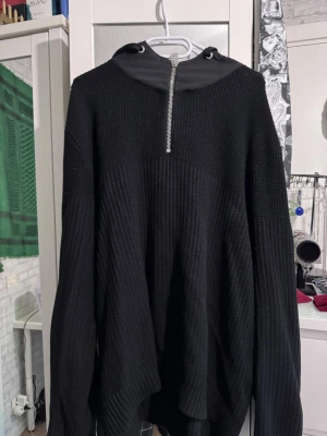 Svart hoodie från HUGO med dragkedja - Säljer en svart hoodie från HUGO med halv dragkedja framtill och huva med snörning. Tröjan är ribbstickad och har en patch med HUGO-loggan på ärmen. Perfekt för en chill och stilren look. Se sista bild!