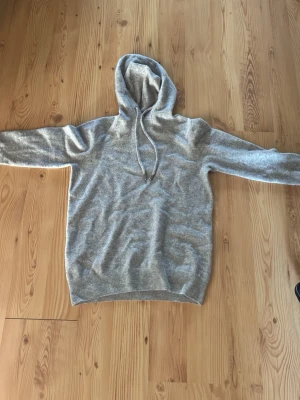Grå merinoull hoodie - Säljer en grå merinoull hoodie i storlek S. Den har ett litet hål någon stans som man inte alls ser. och är i bra skick. Bara att höra av sig vid frågor eller funderingar