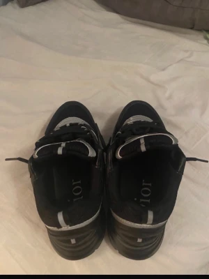 B22 Svarta chunky sneakers   - Säljer ett par svarta chunky sneakers  med vita och grå detaljer. Skorna har en sportig design med meshpaneler och robust sula. -loggan syns på sidan och innersulan. Perfekta för dig som gillar streetwear och exklusiva märken.