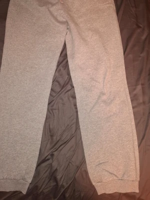 Gråa mjukisbyxor från Nike - Snygga gråa mjukisbyxor från Nike med dragsko i midjan och muddar vid bensluten. Klassisk och enkel design, perfekta för chill eller träning. Tillverkade i mjukt och bekvämt material som känns skönt mot huden. Vet inte om jag använt dem men dem är i nyskick 