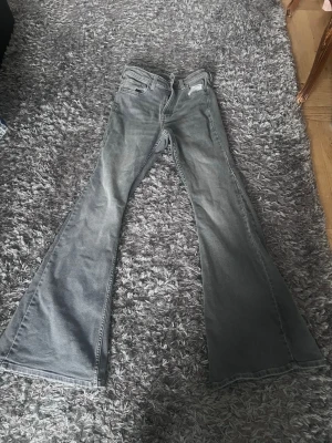 Gråa utsvängda jeans bootcut - Säljer ett par gråa jeans med riktigt breda utsvängda ben, så kallad bootcut-modell. Klassisk femficksdesign och normal midja. Perfekta för dig som du vill ha snygg style. Materialet är denim i bomull.