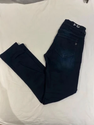 Dondup Mörkblå slim fit jeans - Snygga mörkblå slim fit jeans med klassisk femficksdesign och diskret detalj på bakfickan. Jeansen har en smal passform och är tillverkade i stretchigt denimtyg för extra komfort. Perfekta för en trendig och avslappnad look.