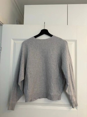 Ljusgrå stickad tröja Noisy May - Ljusgrå stickad tröja från Noisy May med rund halsringning och ribbade muddar vid ärmslut och nederkant. Tröjan har en avslappnad passform