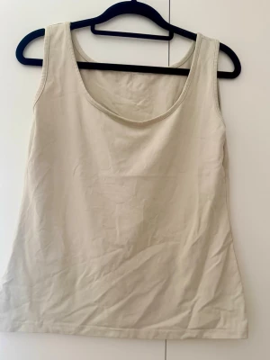 Beige linnetopp med rund hals - Säljer en enkel och stilren beige linnetopp med rundad halsringning. Toppen är ärmlös och har en rak passform, perfekt att matcha med jeans eller kjol. Materialet känns mjukt och bekvämt mot huden.