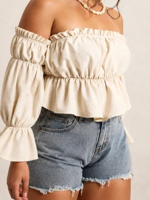Off shoulder  - Superfin offshoulder topp i beige med volangdetaljer och vida ärmar. Toppen har en smockad resår upptill och i midjan för en snygg passform. Perfekt till jeans eller kjol för en trendig look.