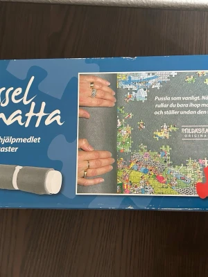 Pusselmatta - Pusselmatta för enkel förvaring och transport av påbörjade pussel och lösa bitar. Mattan rullas ihop och spänns fast. Passar pussel upp till 2000 bitar (98x68 cm).