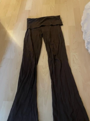 Bruna yoga pants - Säljer ett par bruna yogapants med utsvängda ben och bred linning i midjan. Materialet ser mjukt och stretchigt ut, perfekta för en avslappnad och trendig look. Passar dig som gillar bekväma men ändå snygga byxor.