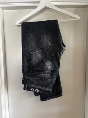 Svarta jeans från dondup med slitningar - Snygga svarta faded jeans med slitningar från dondups perfekt för hösten. Jeansen har en lagning som man kan se på bild 6 men den påverkar inte användningen