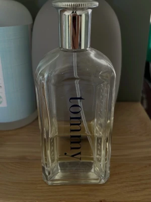 Tommy Hilfiger Tommy EdT 100ml - Fräsch parfym från Tommy Hilfiger, Tommy EdT, i en stilren transparent glasflaska med silverfärgad kork. Doften är klassisk och tidlös, perfekt för dig som gillar en sportig och fräsch känsla. Kommer i originalförpackning med röd, vit och blå design. Halva flaskan