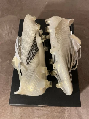  Adidas X Ghosted.1 elite 40 - Säljer ett par stilrena Adidas X Ghosted.1 fotbollsskor i vitt med svarta detaljer. Skorna har låg vikt, snörning och en modern, strömlinjeformad design med genomskinliga inslag. Ovandelen är i syntetmaterial för optimal bollkontroll och grepp på planen. Storlek 40 och är elite versionen bara testade så är jätte bra skick.