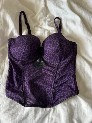 Lila leopardmönstrad korsett - Korsett med lila och svart leopard print med kupor!💜🐆osäker på storlek men passar mig som har storlek S ungefär